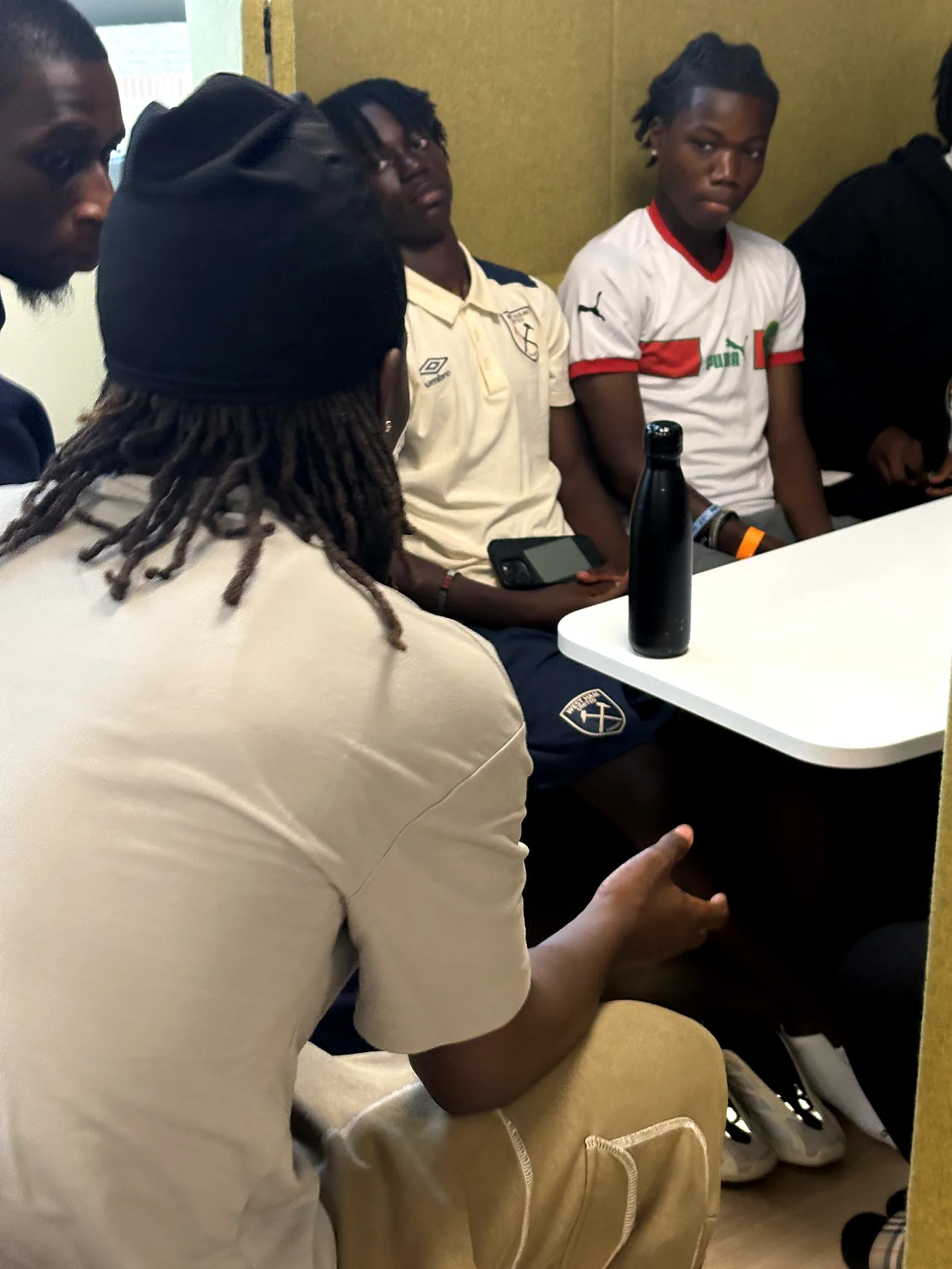 A JDS mentor sitting with a small group of younger people in a booth